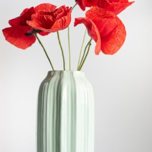 a white vase with red flowers in it